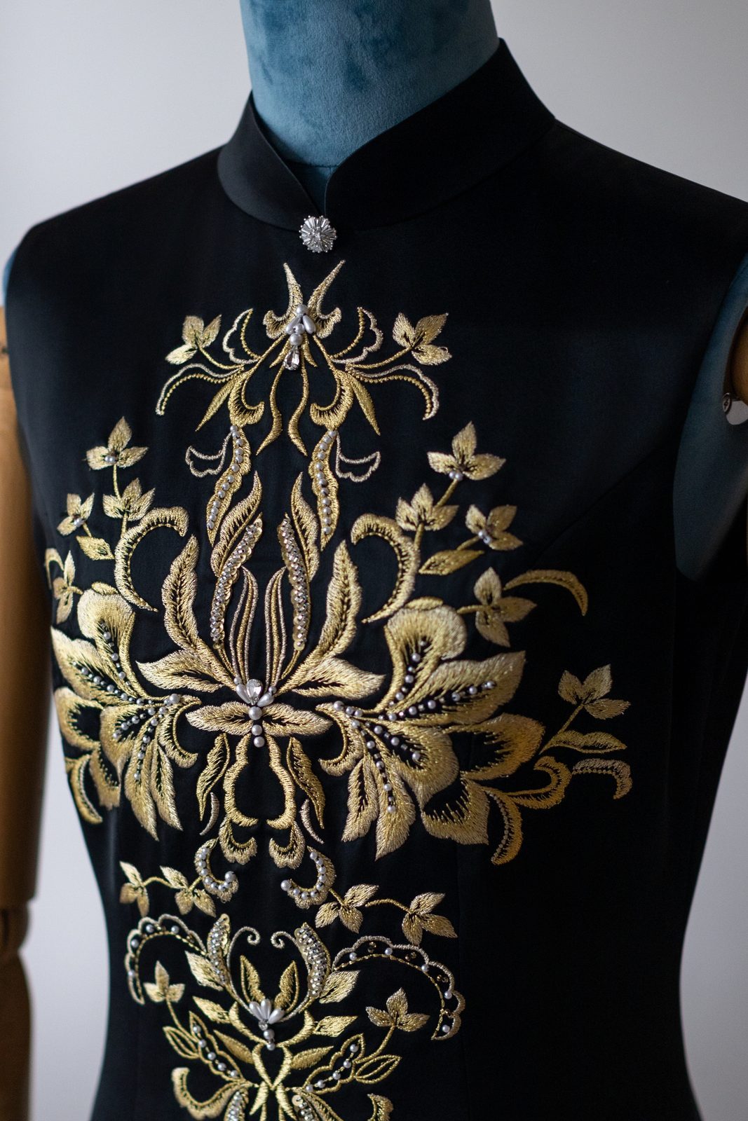 Close-up of gold-thread embroidery and beading on a bespoke black gown