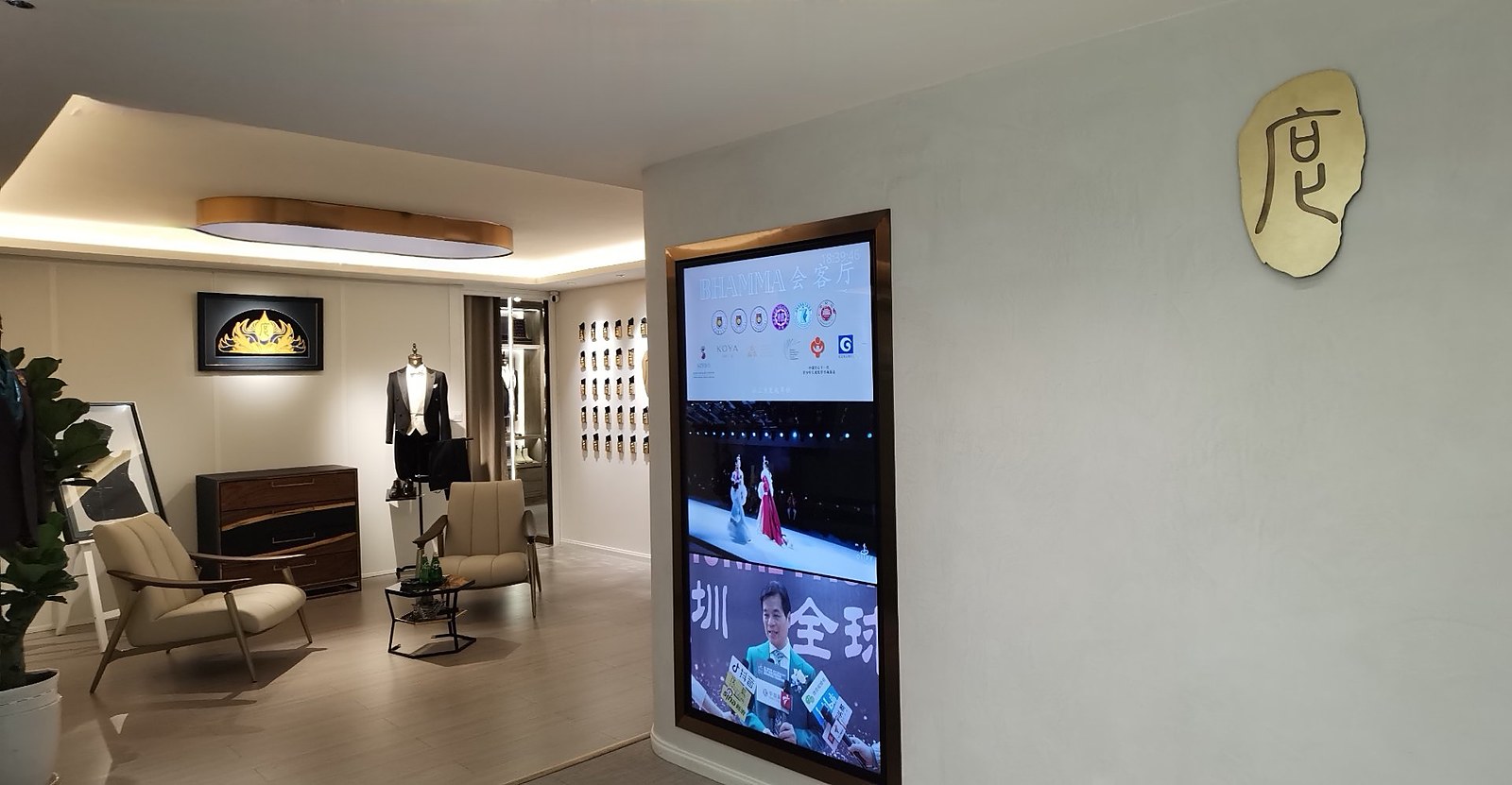度·BESPOKE 深圳门店入口：黄铜「度」字牌、竖屏品牌影像墙，后方为洽谈区与徽章陈列墙